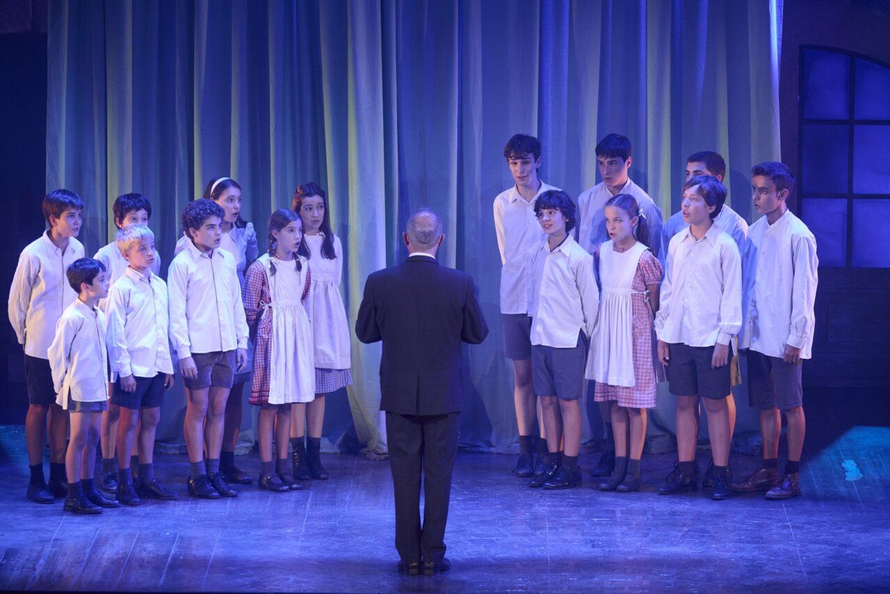 Grupo de niños cantando en el musical Los chicos del coro