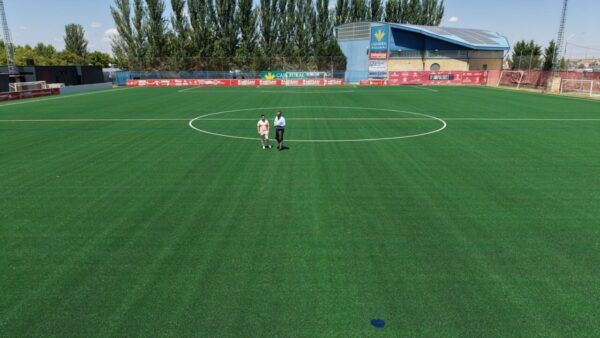 Campo de fútbol Alfonso San Casto con césped renovado y dos personas caminando