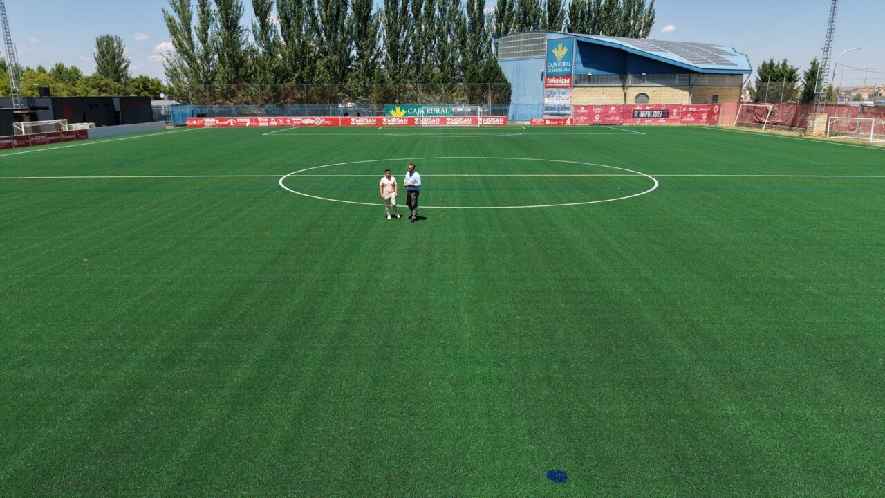 Campo de fútbol Alfonso San Casto con césped renovado y dos personas caminando