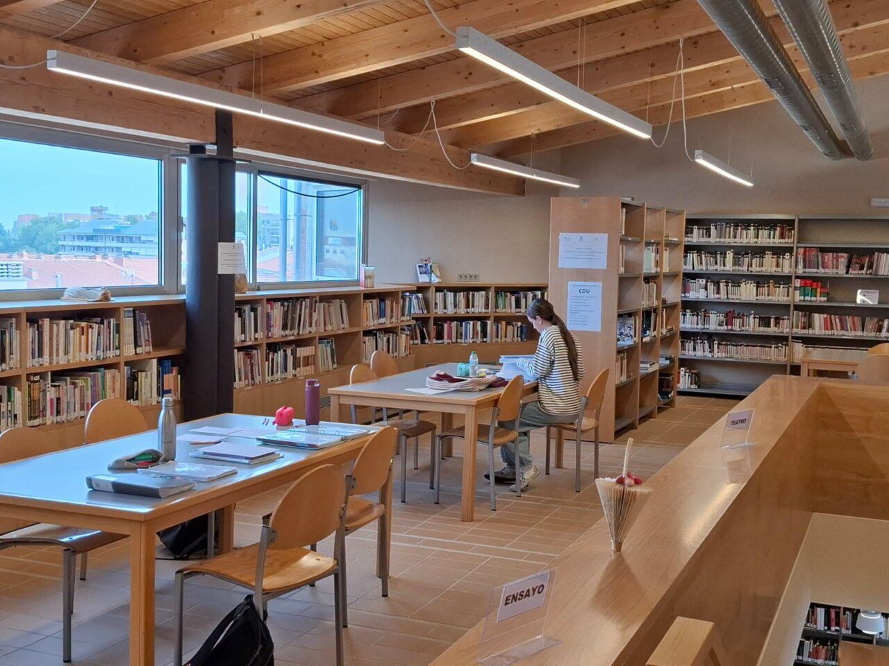 Interior de la biblioteca municipal de Carbajosa con mesas y estanterías