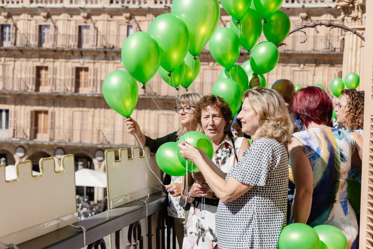 Grupo de personas sosteniendo globos verdes en Salamanca