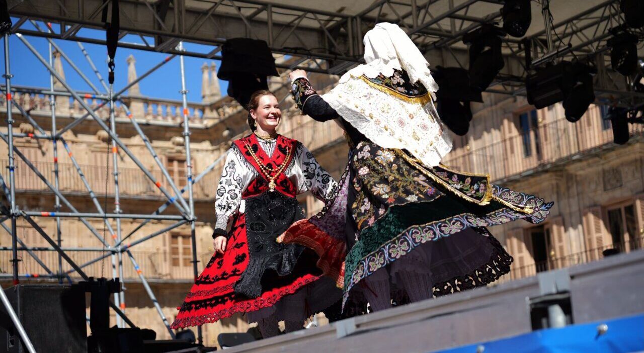 Mujeres bailando con trajes tradicionales en un escenario al aire libre