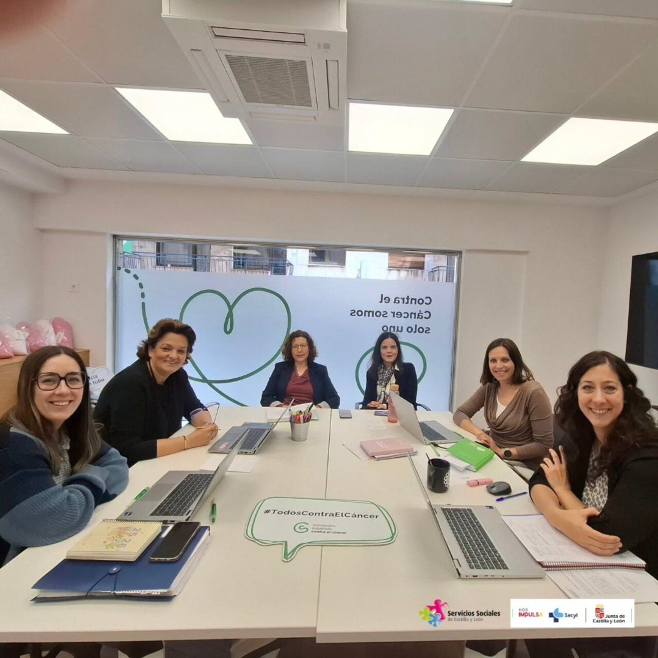 Reunión del equipo de la AECC en Salamanca con laptops y material de trabajo.