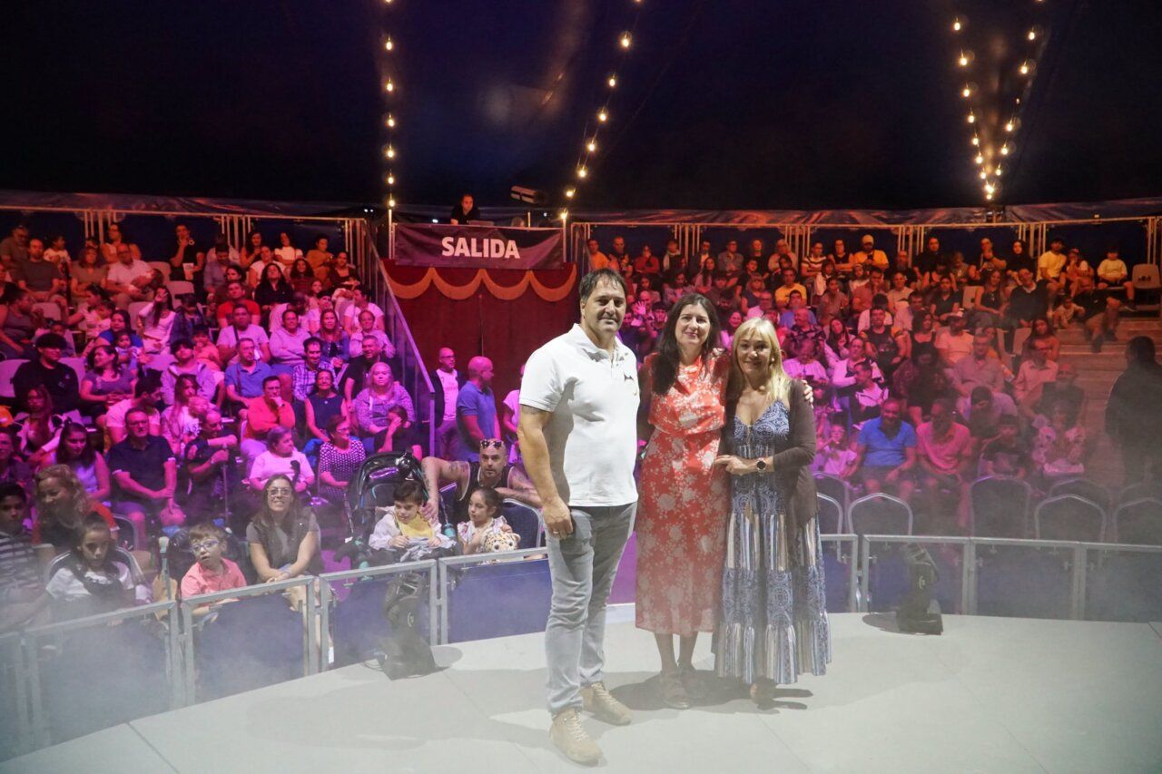 Tres personas posando en un circo con público al fondo