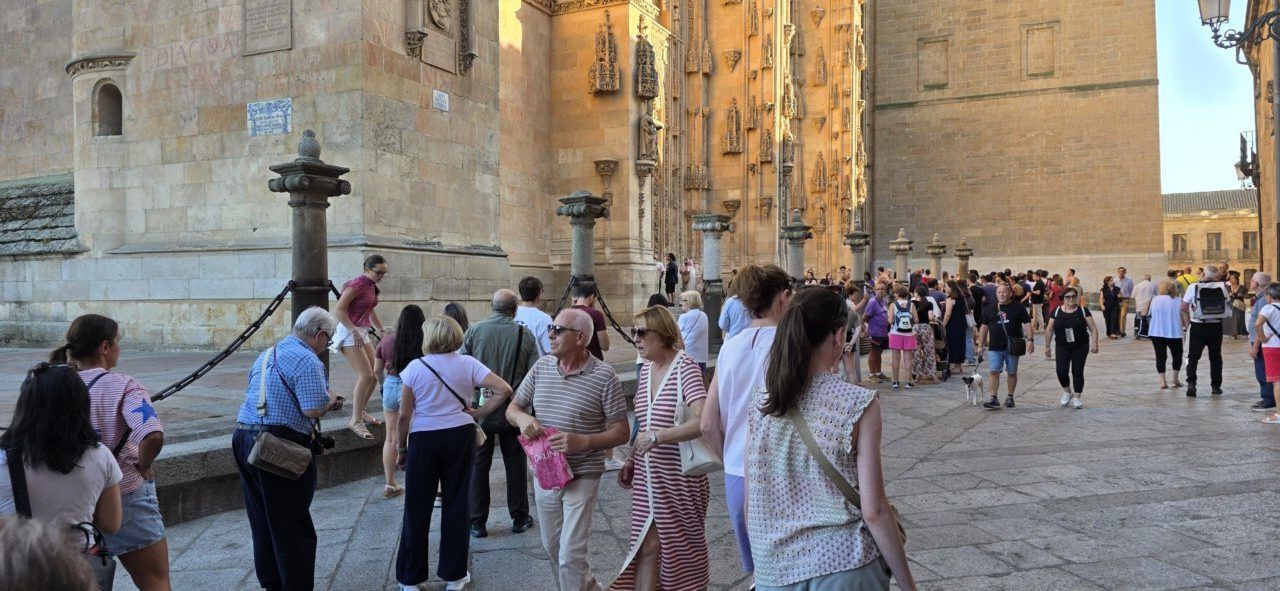 Multitud de personas frente a la catedral de Salamanca en un día soleado.