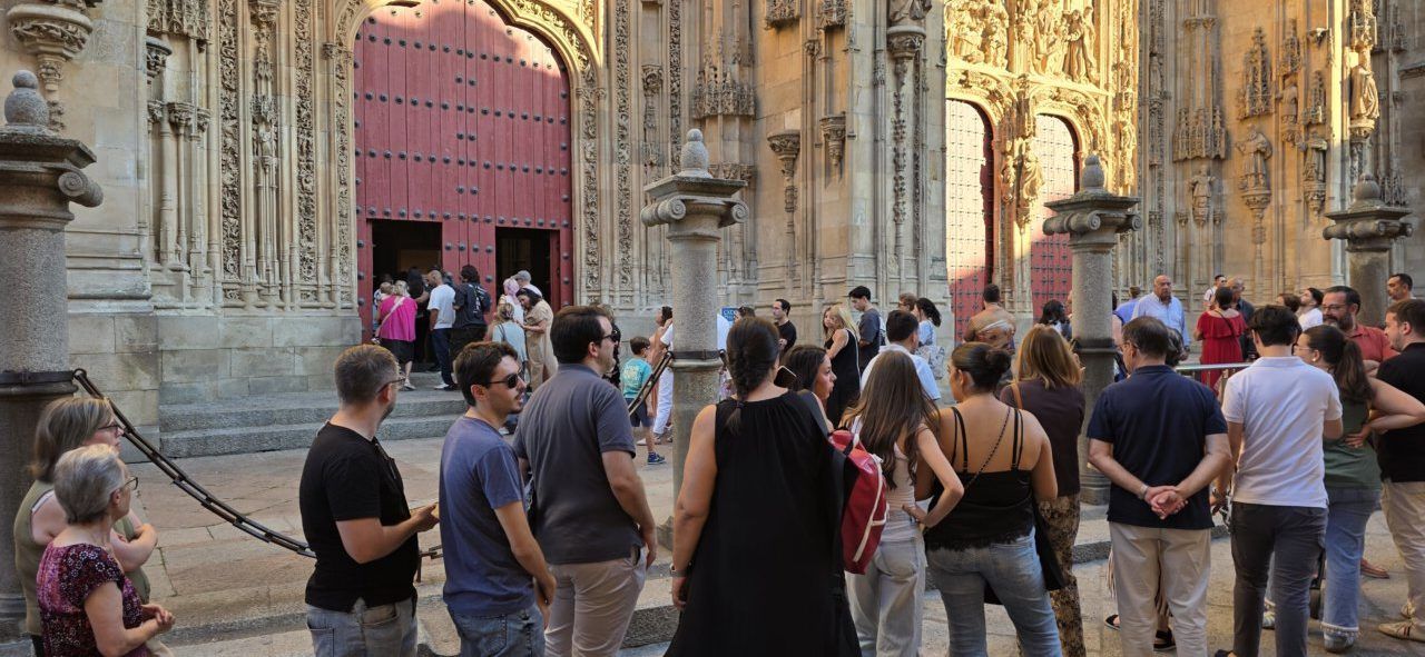 Grupo de personas frente a una puerta decorada con esculturas