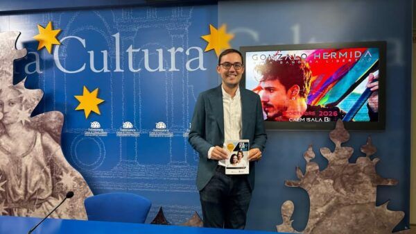 Presentación de la agenda cultural en Salamanca con un hombre sosteniendo un folleto.