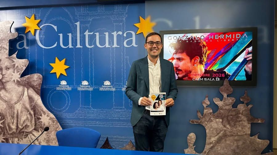 Presentación de la agenda cultural en Salamanca con un hombre sosteniendo un folleto.