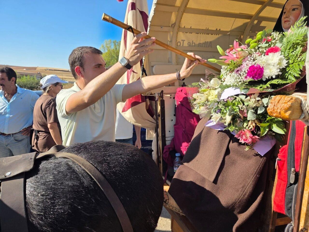 Hombre colocando flores en un carro durante la marcha teresiana