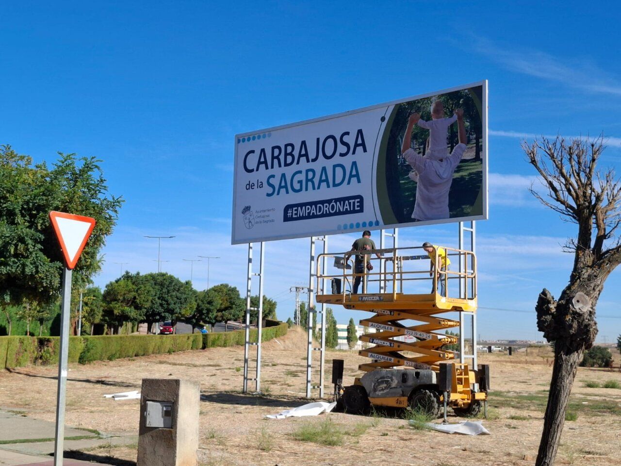 Trabajadores instalando un cartel de la campaña Empadrónate en Carbajosa de la Sagrada.