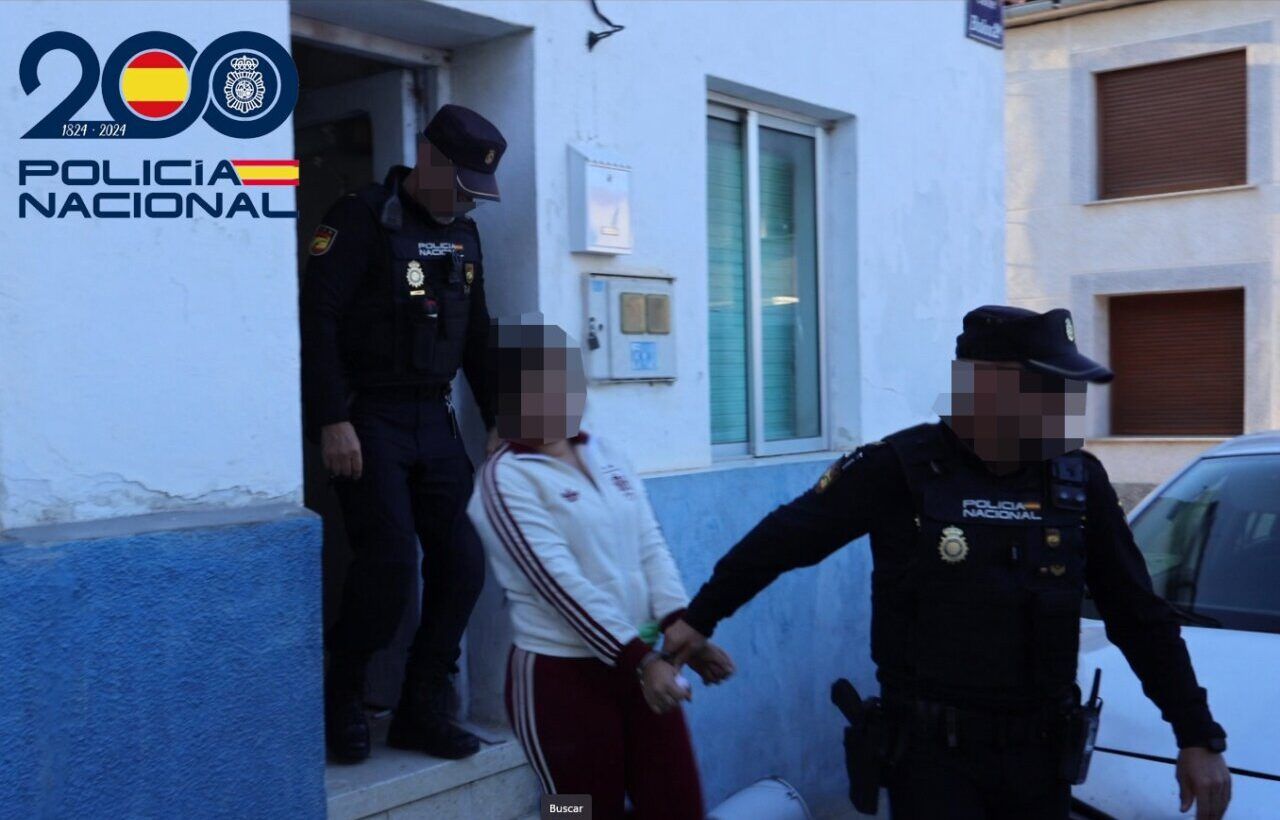 Agentes de la Policía Nacional escoltan a una persona pixelada junto a un portal.