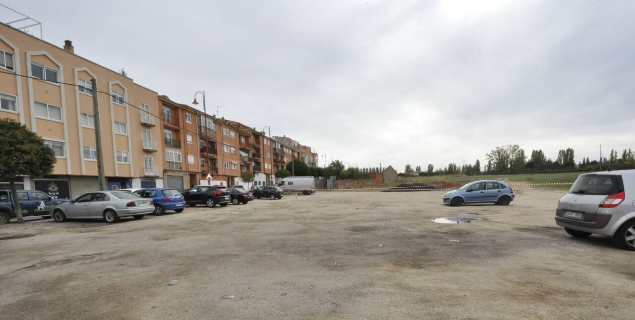 Aparcamiento al aire libre con varios coches frente a bloques de viviendas
