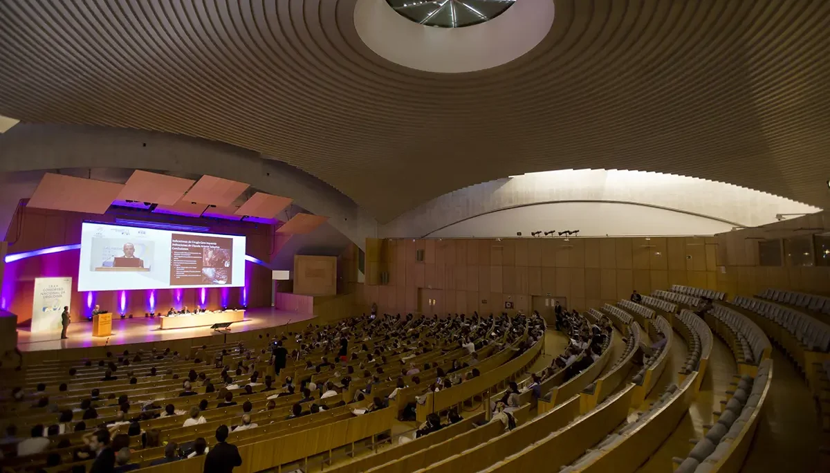 Vista amplia de un auditorio con público sentado frente a un escenario iluminado.