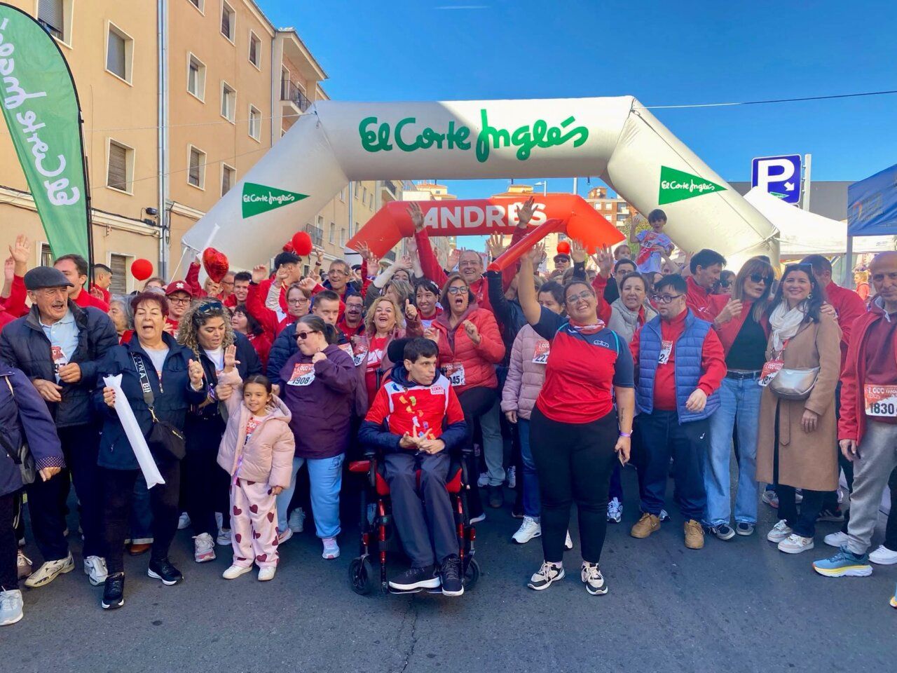 Participantes y asistentes se reúnen bajo un arco de salida en una carrera urbana.