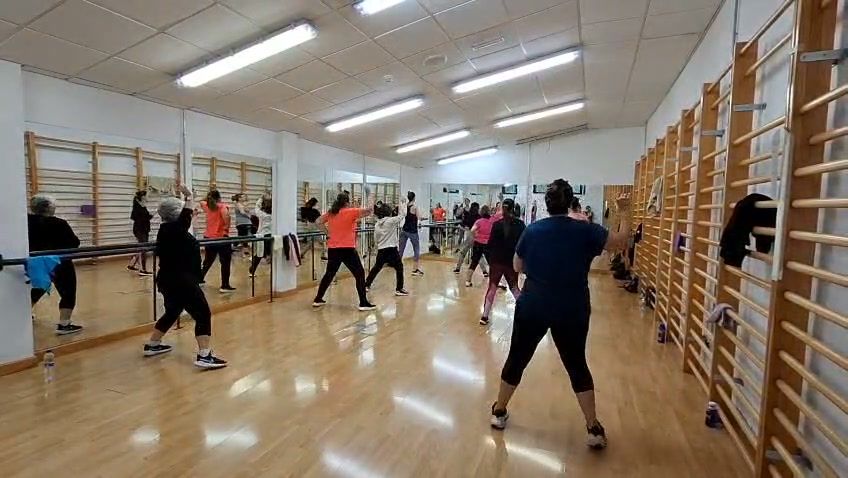 Catorce vecinas participando en una clase de Zumba en el Pabellón Municipal