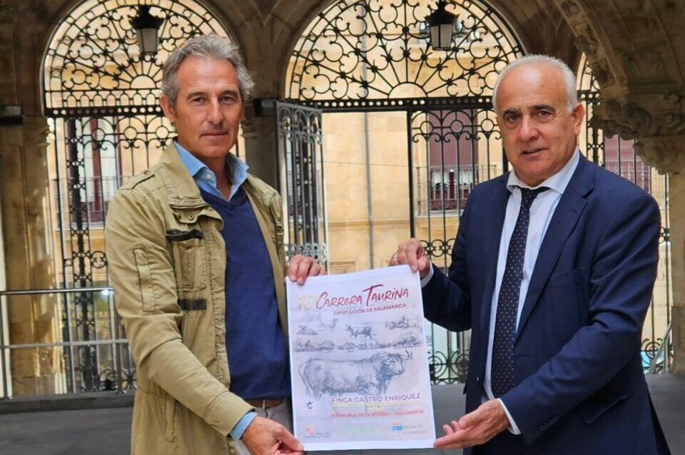 Dos hombres sostienen el cartel de la X Carrera Taurina bajo unos arcos de piedra.