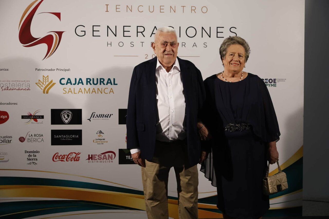 Dos personas posan frente al panel del Encuentro de Generaciones Hosteleras