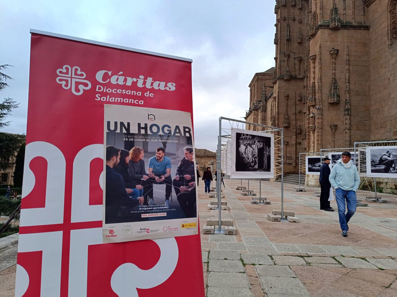 Exposición fotográfica junto a un cartel de Cáritas Salamanca, frente a la Catedral.