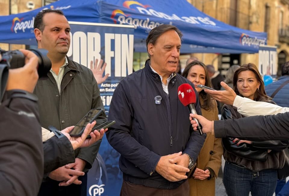 Fotografía de un hombre atendiendo a varios micrófonos bajo una carpa del PP.