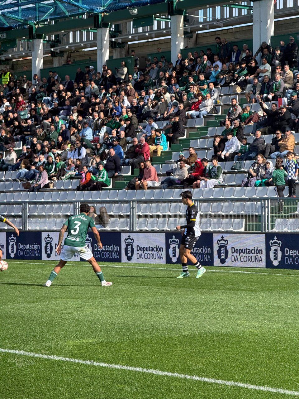Dos futbolistas se encuentran en el campo frente a una grada llena de espectadores.