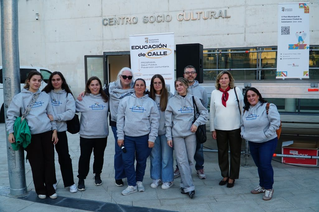 Grupo de personas posa frente al centro sociocultural junto al cartel Educación de Calle.