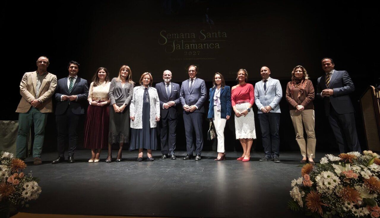 Grupo de personas posa en un escenario ante una proyección de Semana Santa Salamanca 2027.
