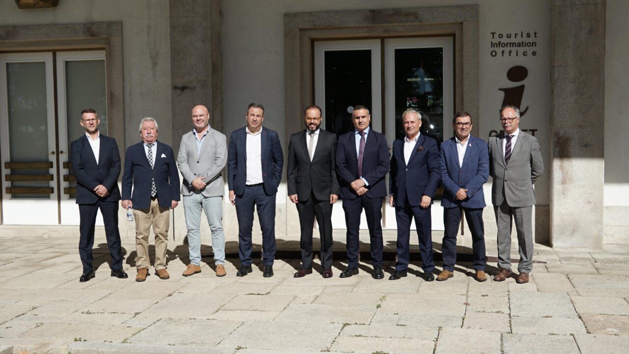 Diez hombres posan frente a la entrada de una oficina de información turística.