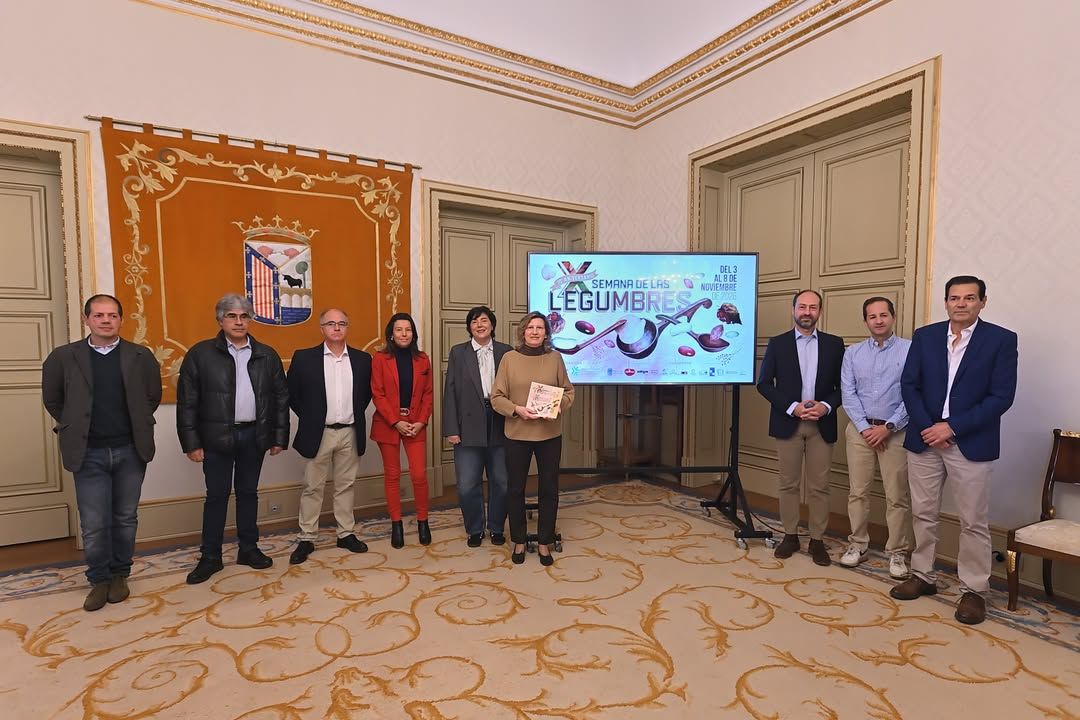 Grupo de personas posa junto a una pantalla con el cartel de las legumbres