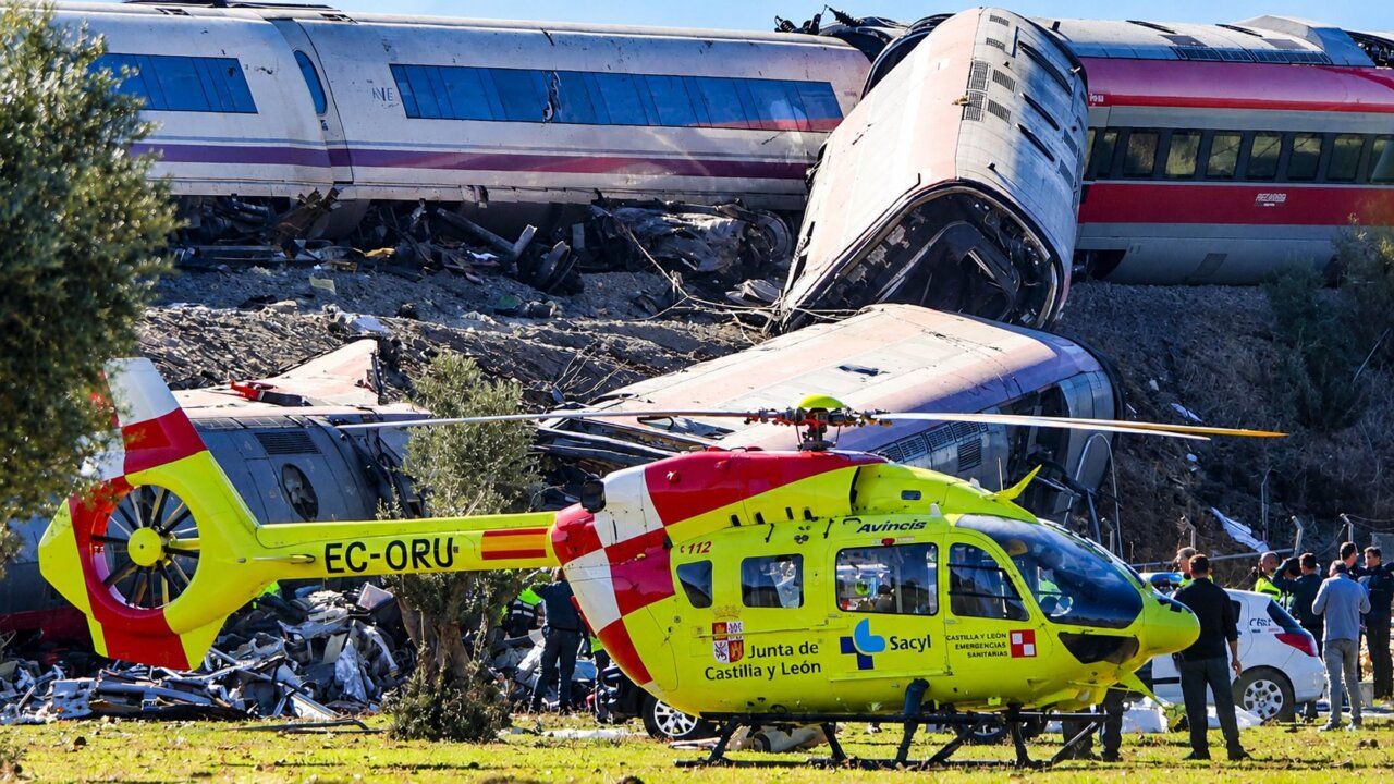 Helicóptero de emergencias frente a varios vagones de tren descarrilados.