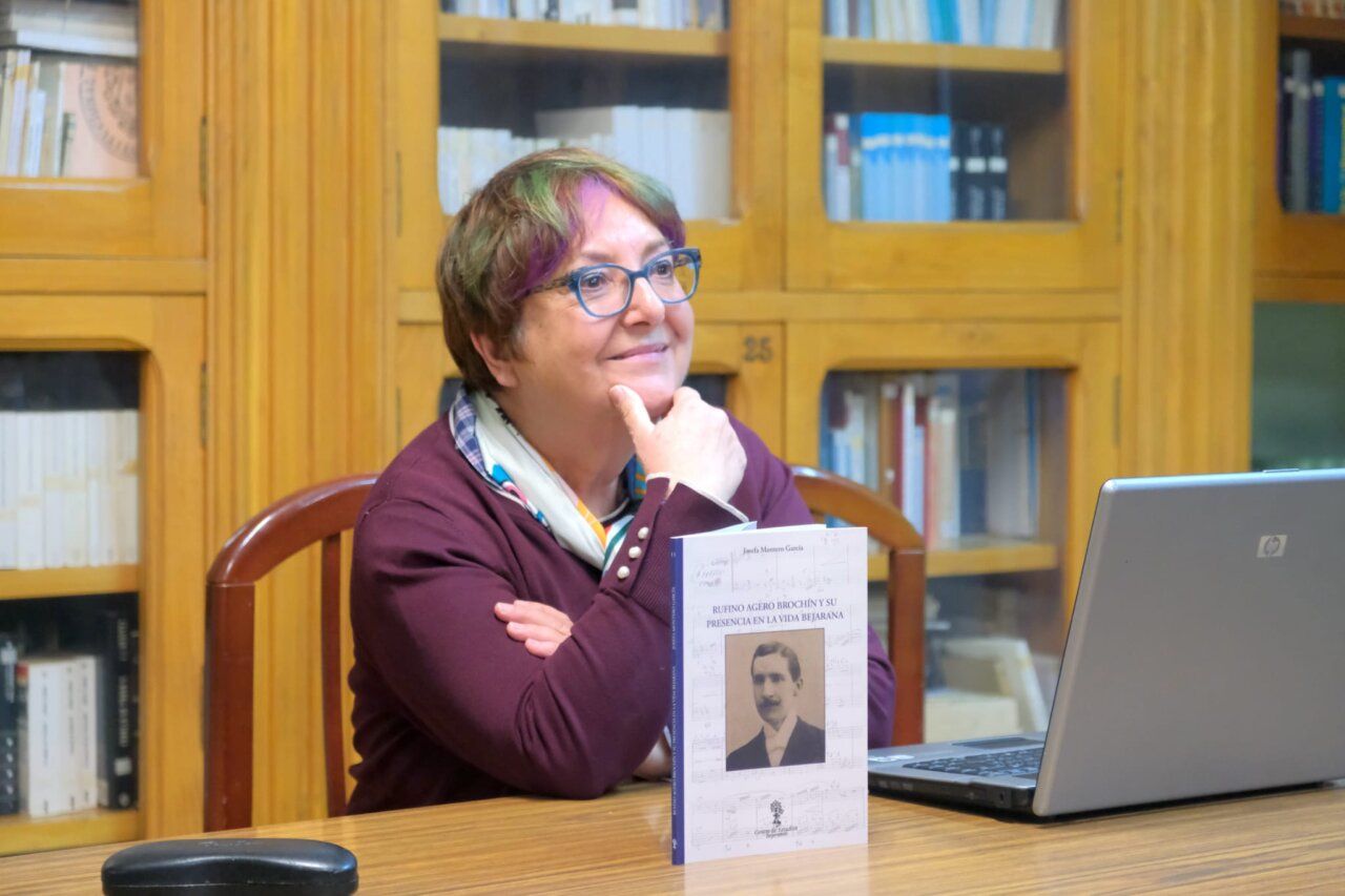 Mujer sentada junto a un libro sobre Rufino Agero y un ordenador portátil