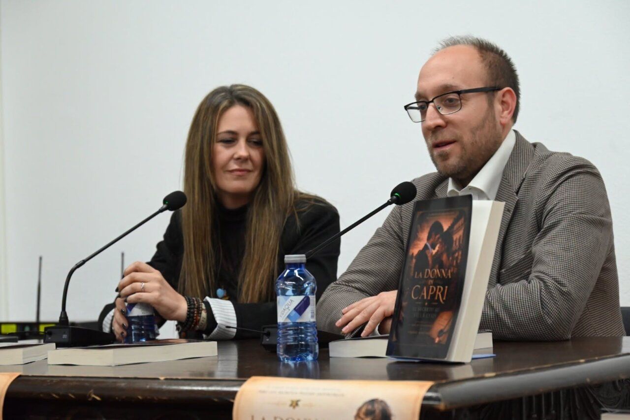 Dos personas sentadas ante micrófonos, con ejemplares de un libro sobre la mesa.