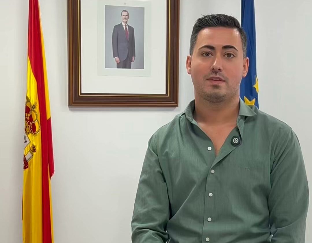 Hombre sentado en un escritorio con banderas de España y Europa