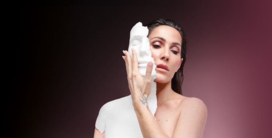 Retrato de una mujer sosteniendo junto al rostro una máscara blanca