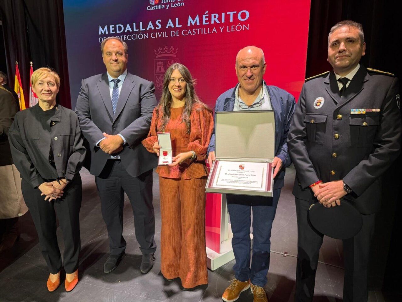 Cinco personas posan con medallas y un diploma ante un fondo de Protección Civil.