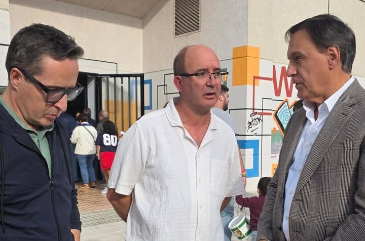 Tres hombres conversando en el pabellón durante un evento deportivo