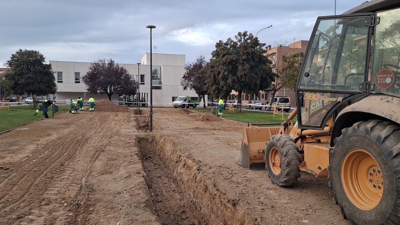 Obras de excavación en un parque, con operarios y una máquina cargadora