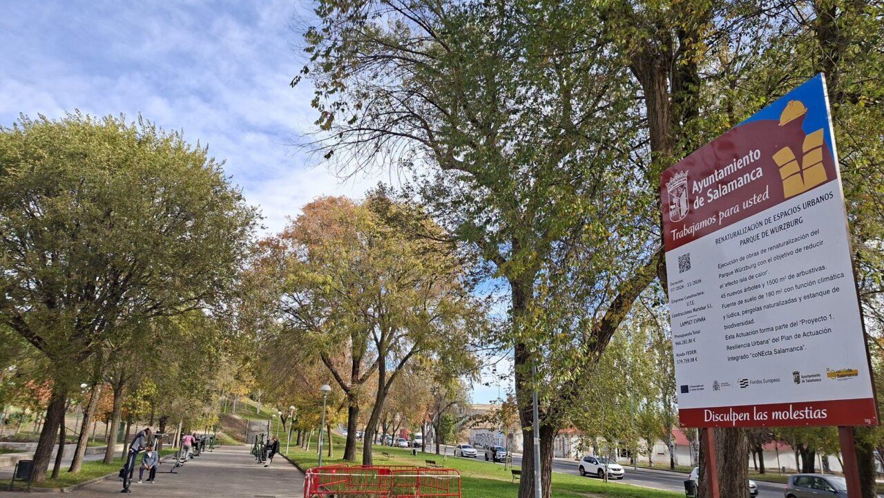 Paseo arbolado junto a un cartel municipal de obras en un parque de Salamanca