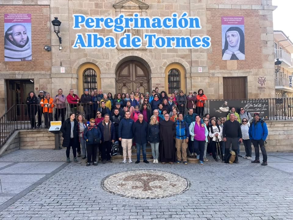 Grupo de personas posa ante un edificio histórico bajo el rótulo Peregrinación Alba de Tormes.