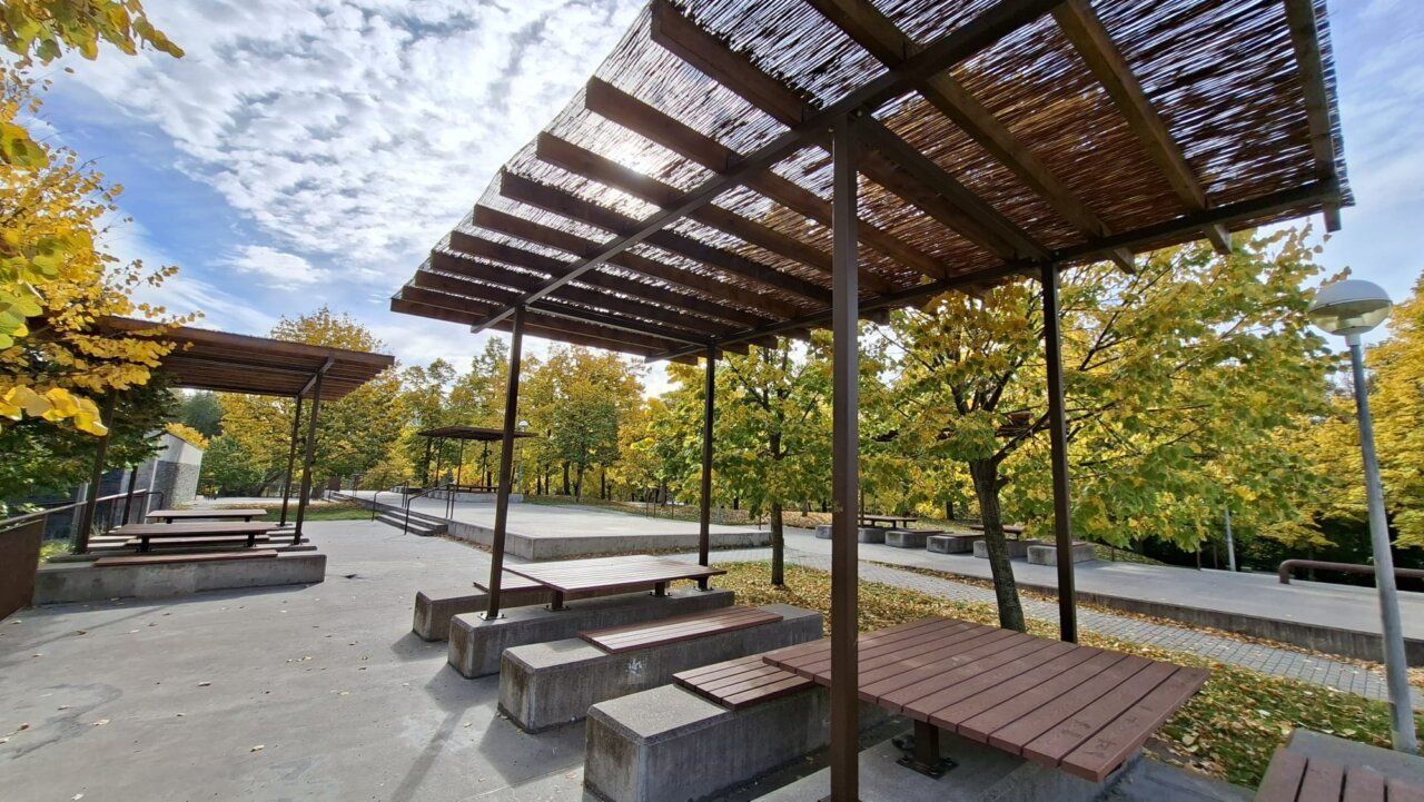 Pérgolas de madera y mesas de picnic en una zona arbolada del parque