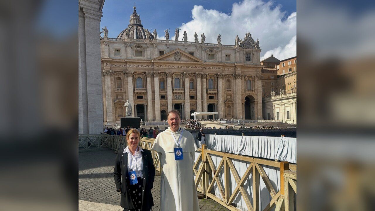 Dos personas posan ante la fachada de la basílica de San Pedro en el Vaticano.