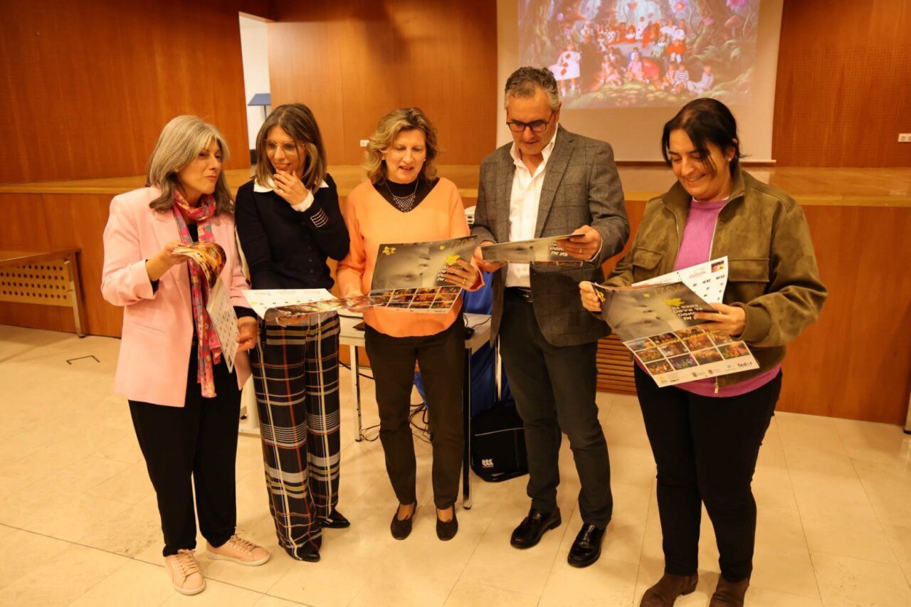 Cinco personas sostienen calendarios impresos en una sala con una imagen proyectada.