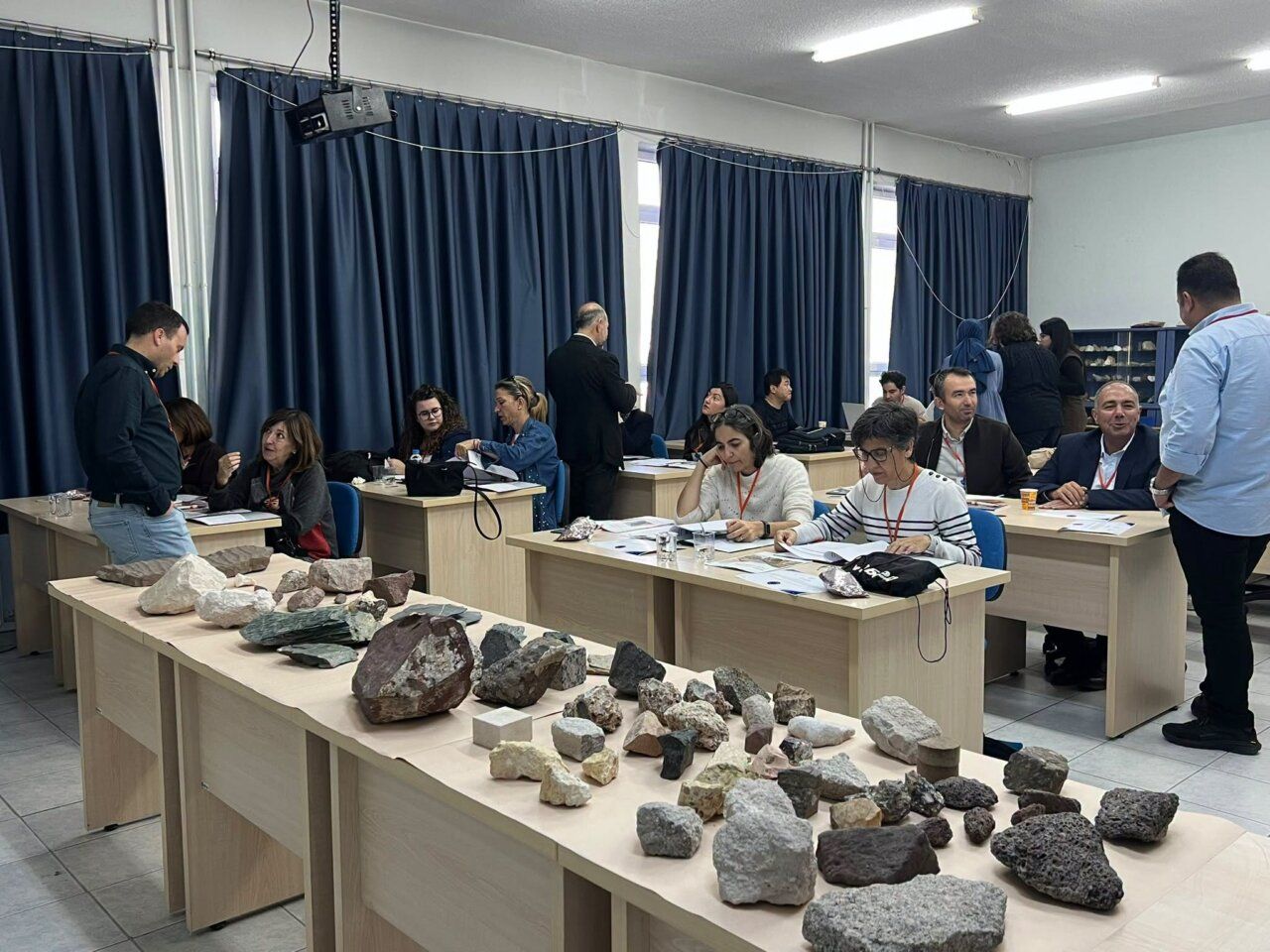 Personas reunidas en una sala con muestras de rocas dispuestas sobre una mesa