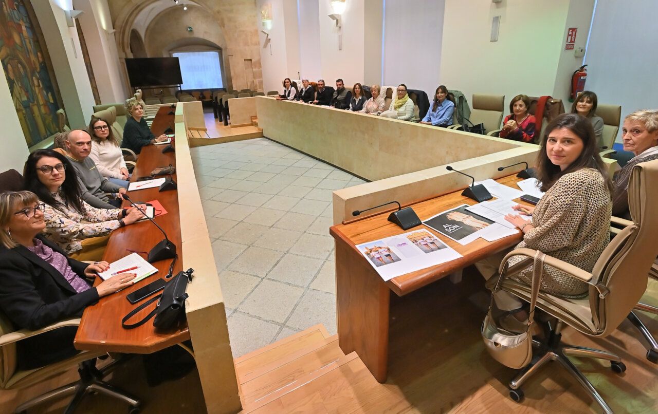 Varias personas sentadas alrededor de una mesa en forma de U durante una reunión