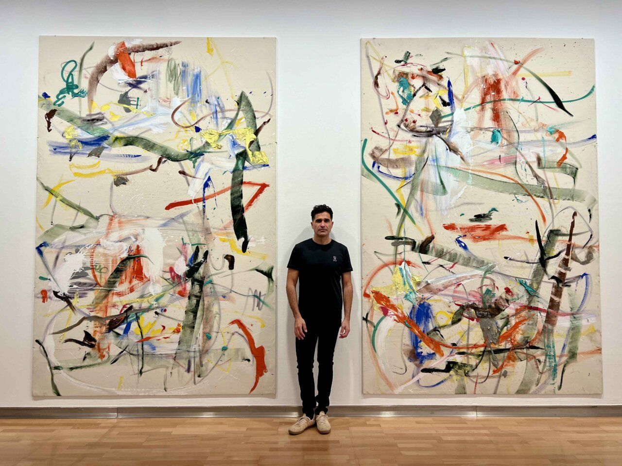 Dos pinturas abstractas de gran formato flanquean a un hombre en una sala