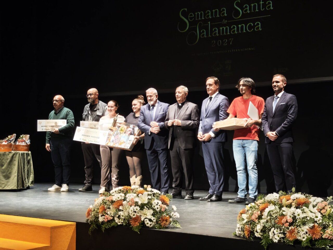 Personas posan en un escenario con premios bajo el rótulo Semana Santa de Salamanca