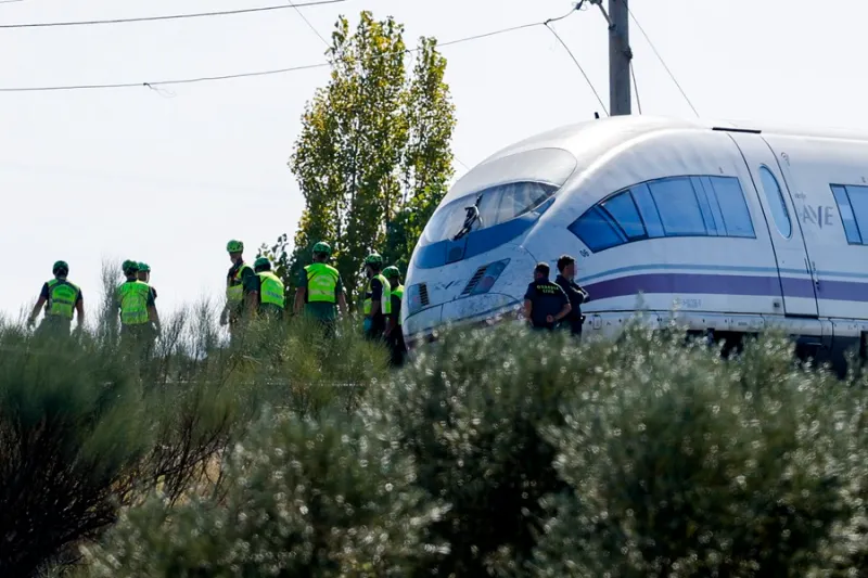 Tren de alta velocidad junto a varias personas con chalecos reflectantes en las vías