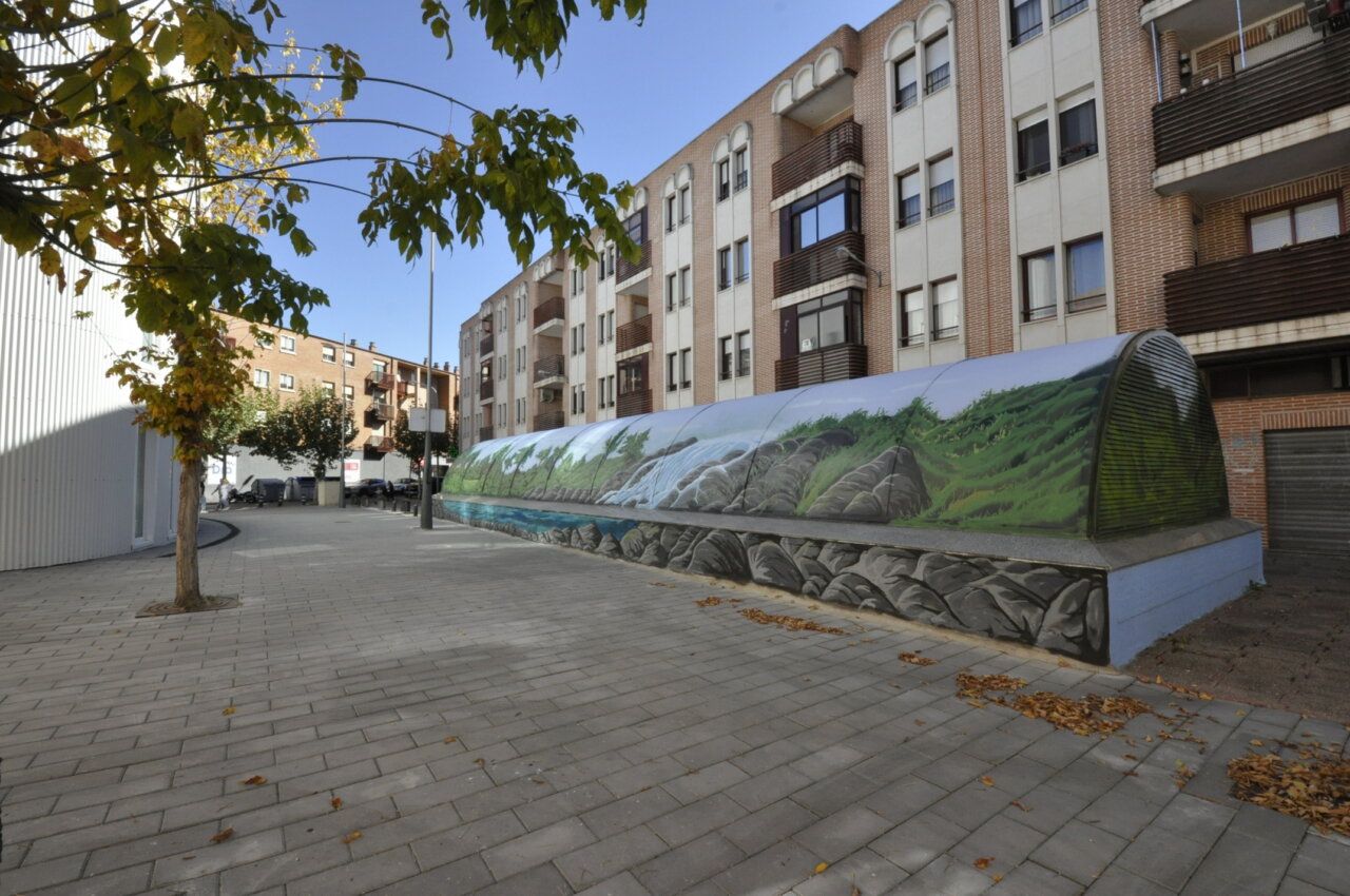 Fotografía de un túnel urbano cubierto por un mural de vegetación, rocas y agua.