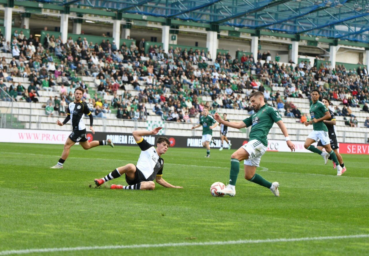 Futbolistas disputan el balón sobre el césped ante una grada llena.